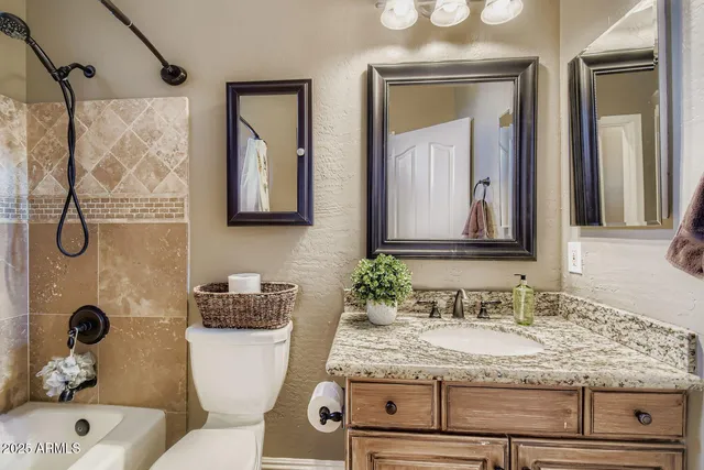 a bathroom with a granite countertop sink mirror vanity and toilet
