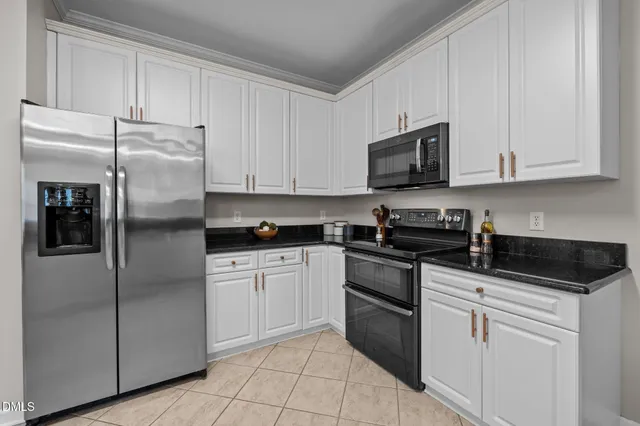 a kitchen with stainless steel appliances kitchen island granite countertop a stove a refrigerator a sink a dining table and chairs with white cabinets