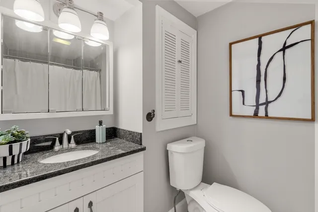 a bathroom with a granite countertop toilet sink and mirror