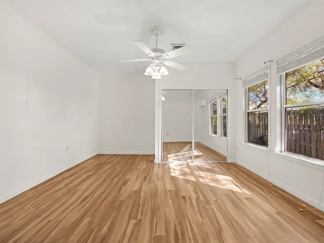 a view of an empty room with window and wooden floor