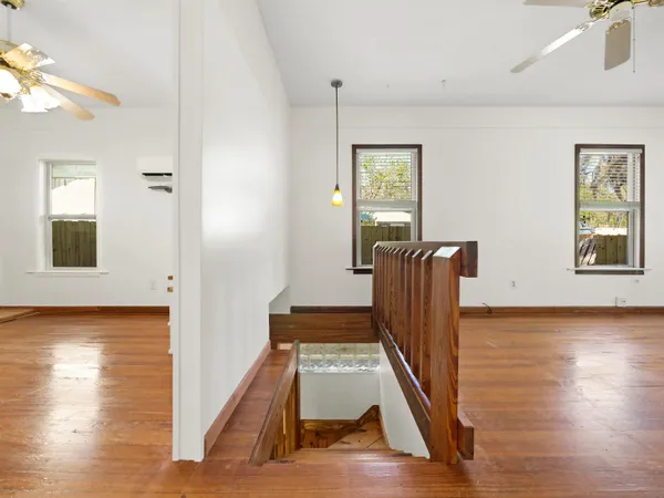 a view of an empty room with window and wooden floor