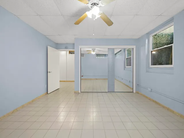 an empty room with fan and windows
