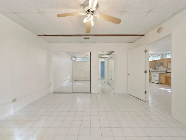 an empty room with chandelier fan and windows