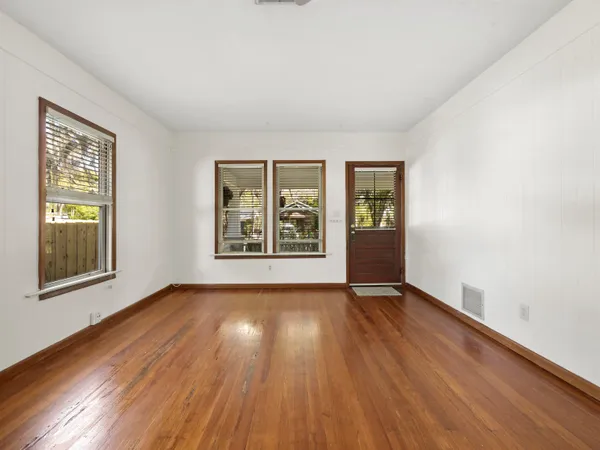 an empty room with wooden floor and windows