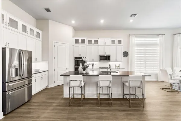 a kitchen with stainless steel appliances kitchen island granite countertop a dining table chairs refrigerator and sink