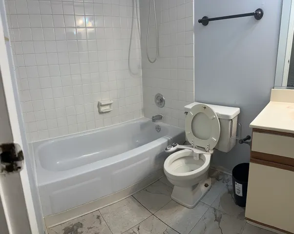 a white toilet sitting next to a bath tub