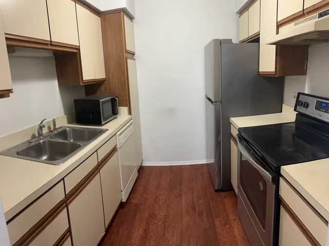 a kitchen with stainless steel appliances a sink dishwasher a refrigerator a stove and white cabinets with wooden floor