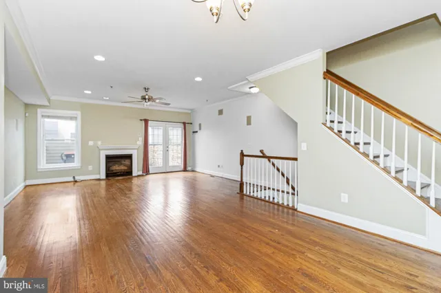 a view of an empty room with wooden floor fireplace and a window