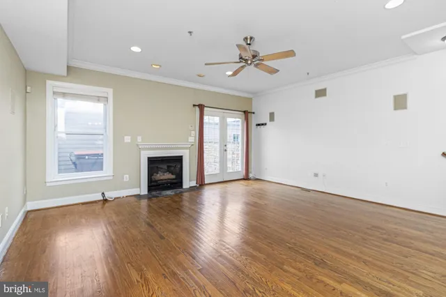 an empty room with wooden floor fireplace and windows