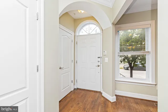 an empty room with wooden floor mirror and windows