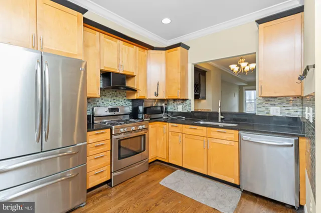 a kitchen with stainless steel appliances granite countertop a refrigerator a stove and a sink with wooden floor