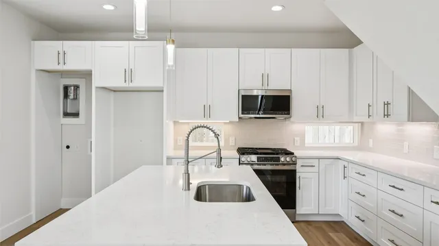 a kitchen with granite countertop white cabinets and stainless steel appliances