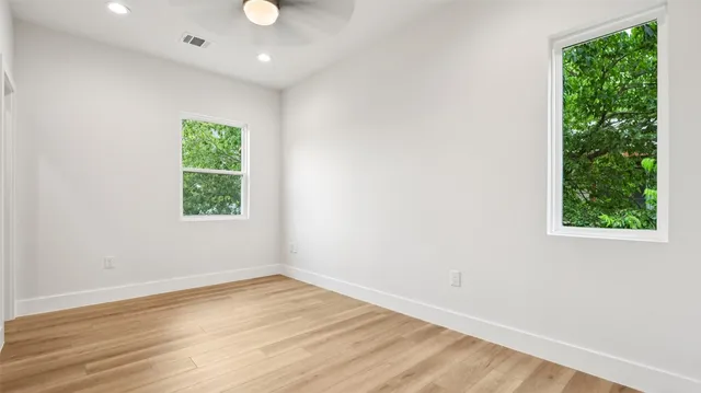 an empty room with wooden floor and windows