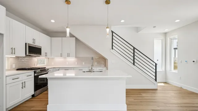 a kitchen with stainless steel appliances kitchen island granite countertop a sink a stove and cabinets