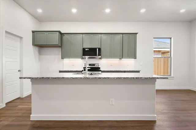 a kitchen with stainless steel appliances granite countertop a sink a stove a microwave a counter top space and cabinets