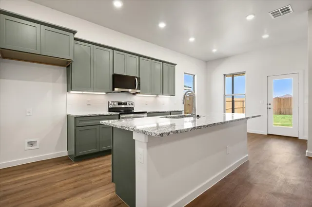 a kitchen with stainless steel appliances granite countertop a stove a sink and a refrigerator