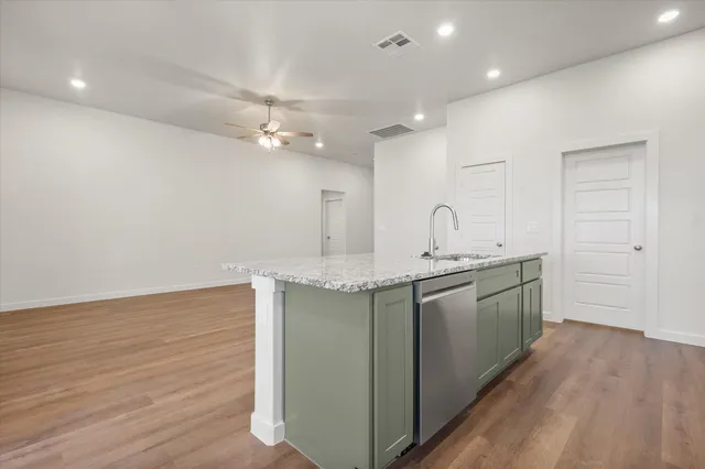 a kitchen with granite countertop a sink cabinets and wooden floor