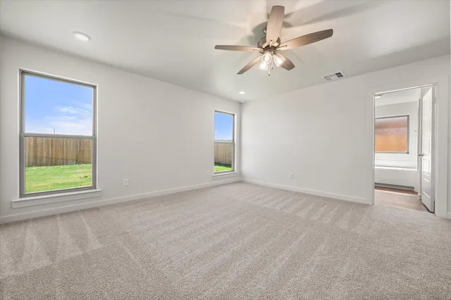 an empty room with windows and fan