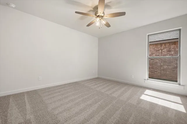 an empty room with a chandelier fan and windows