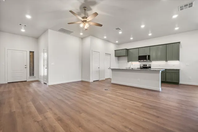 a view of kitchen with kitchen island stainless steel appliances a sink cabinets and wooden floor