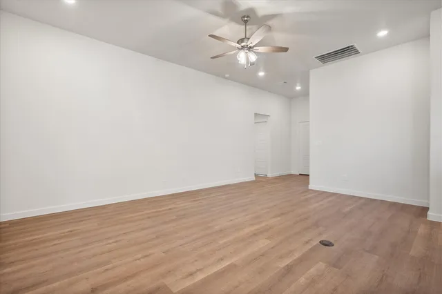 an empty room with wooden floor and fan