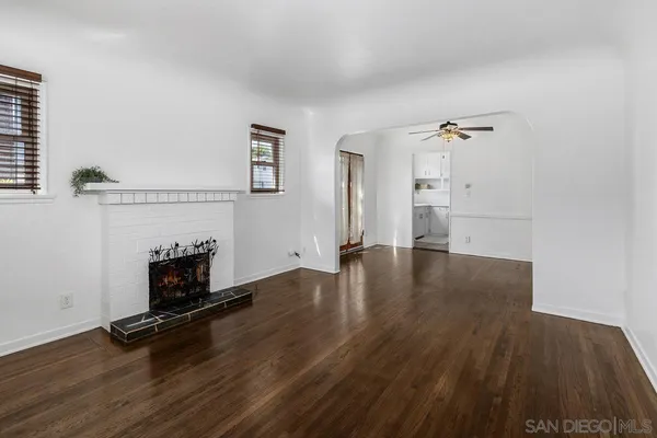 an empty room with wooden floor fireplace and windows