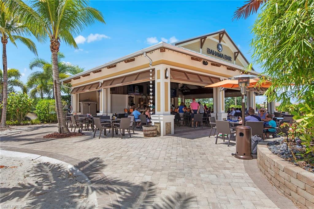 9366 Pocida Court, Unit 202 Naples, FL 34119 - Photo 33 of 44 a view of a patio with table and chairs under an umbrella