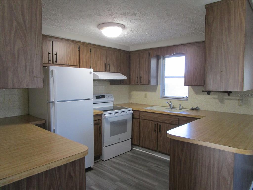 8947 Cairo Lane Port Richey, FL 34668 - Photo 12 of 17 a kitchen with a refrigerator sink and cabinets