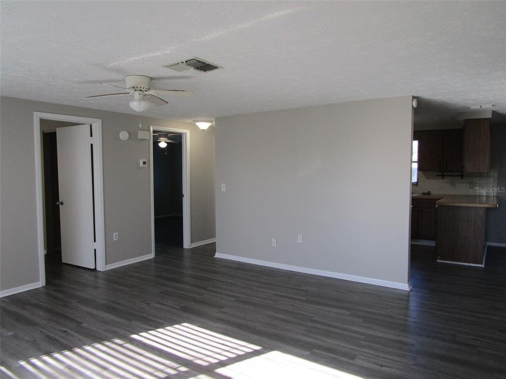 8947 Cairo Lane Port Richey, FL 34668 - Photo 3 of 17 a view of an empty room with wooden floor and a ceiling fan