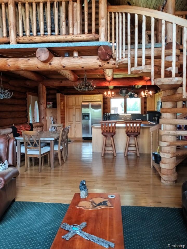 10374 Wilson Road Otisville, MI 48463 - Photo 47 of 99 Living area featuring light wood-style floors, log walls, beam ceiling, and a towering ceiling