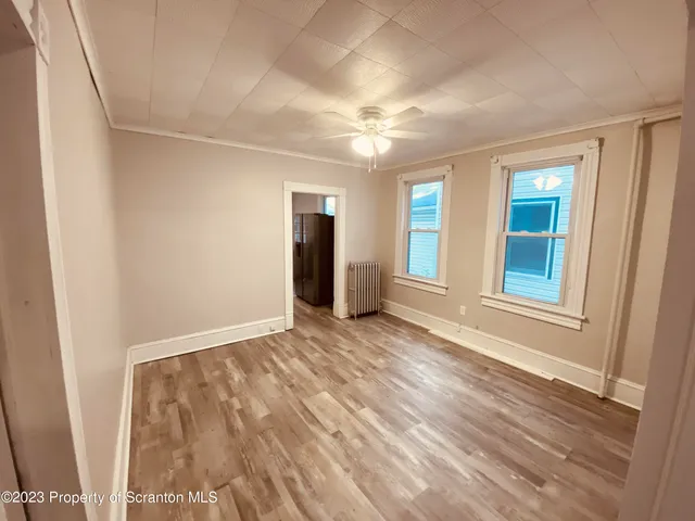 a view of an empty room with window and wooden floor