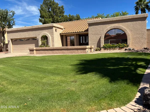 a view of a white house with a yard plants and large tree