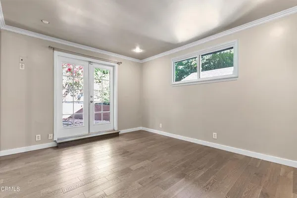 a view of an empty room with wooden floor and a window