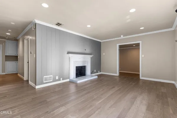 a view of an empty room with wooden floor and a fireplace