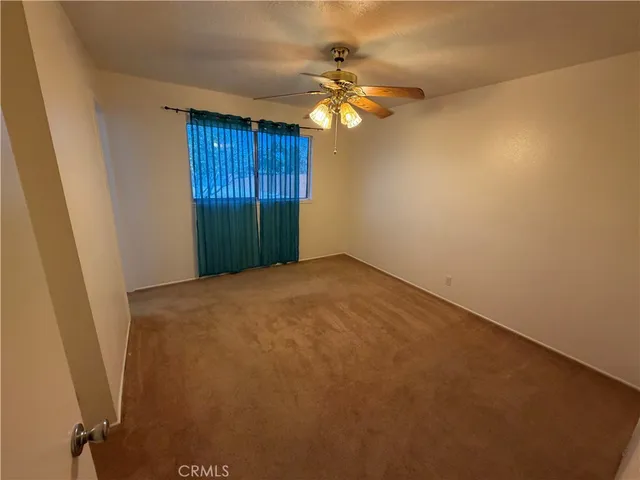 an empty room with a fan & a chandelier fan