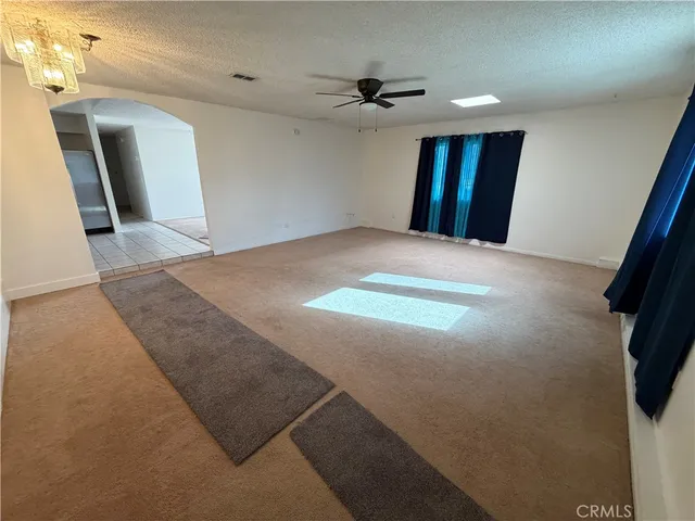 a view of an empty room with window and a kitchen