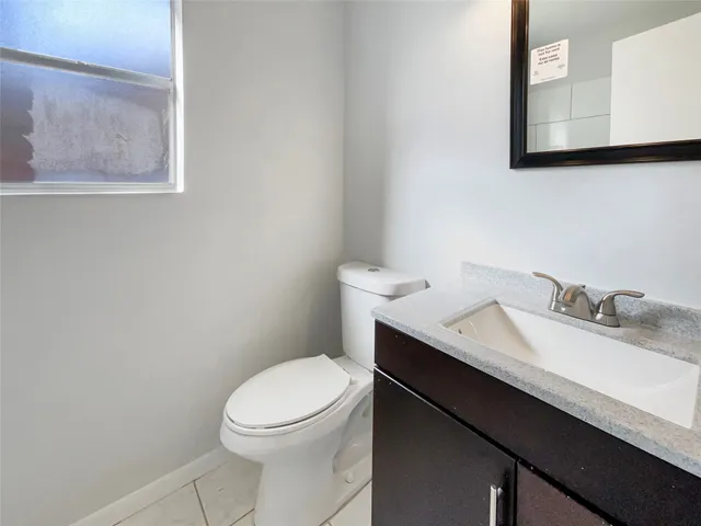 a bathroom with a granite countertop toilet sink and mirror