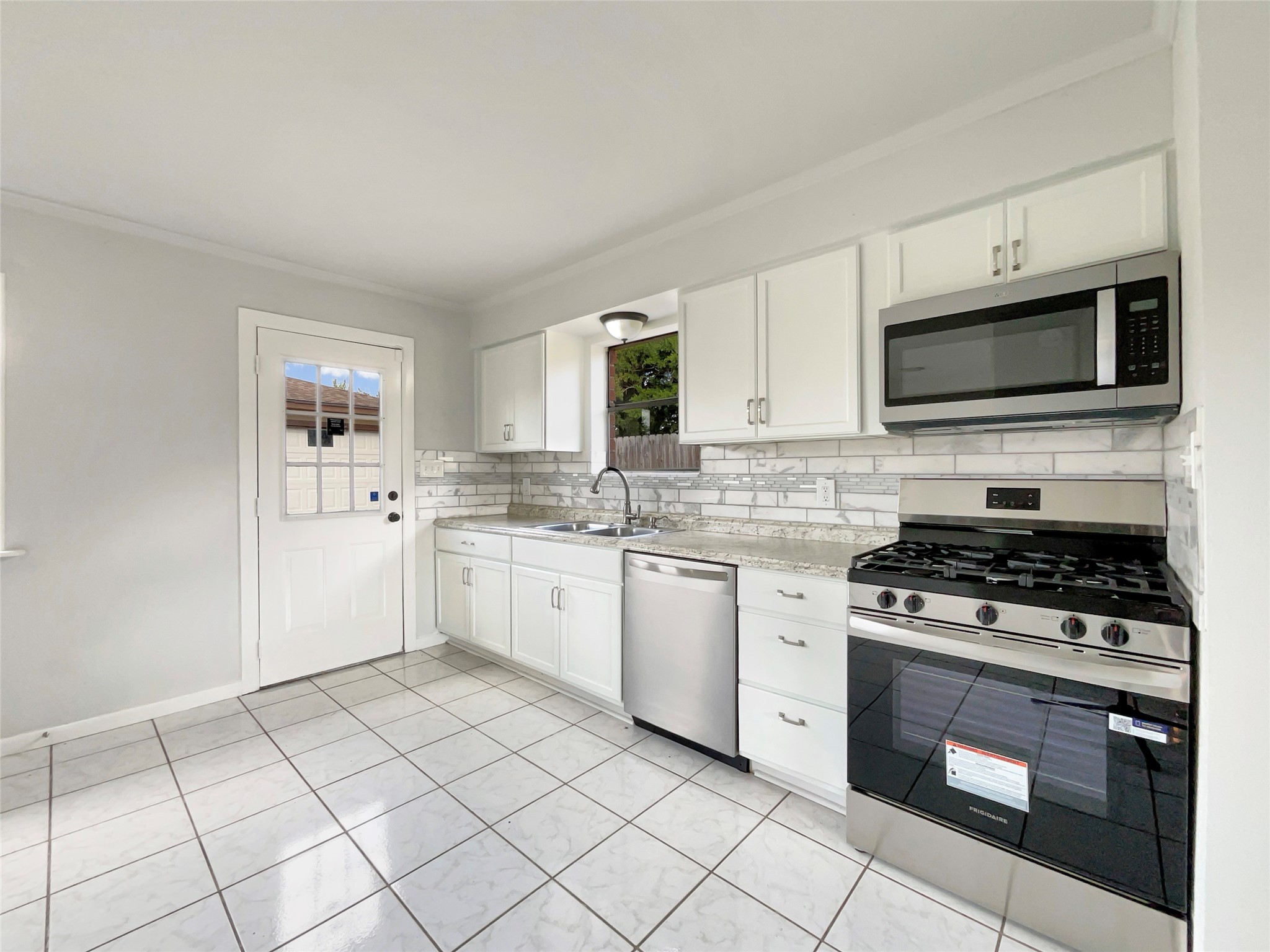 205 Bastrop Street Angleton, TX 77515 - Photo 9 of 18 a white kitchen with stainless steel appliances granite countertop a stove a sink and a microwave