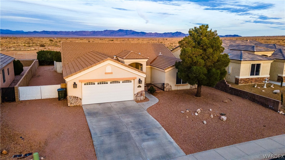 3374 Roma Road Kingman, AZ 86401 - Photo 23 of 64 View of front of house featuring stone siding, stucco siding, driveway, and a gate