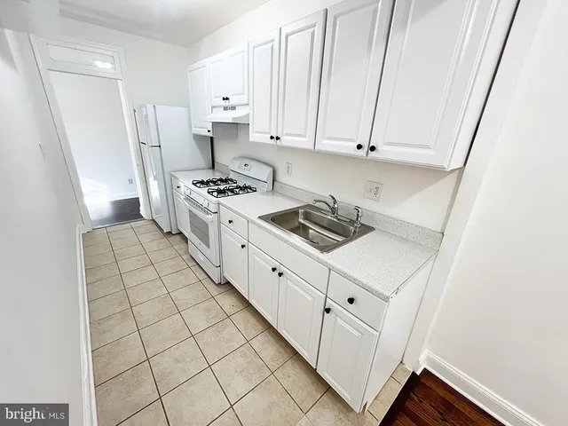 a kitchen with white cabinets a sink stove and refrigerator