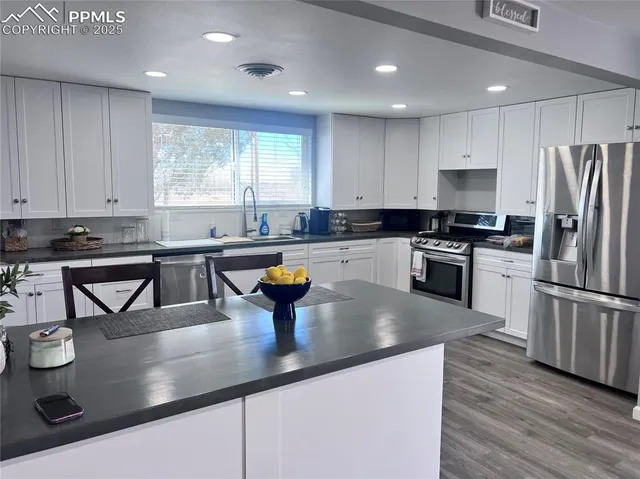 a kitchen with stainless steel appliances granite countertop a sink a stove and a refrigerator