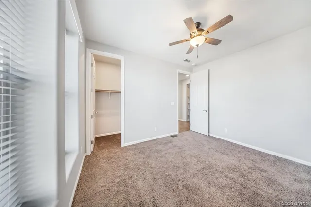 an empty room with closet and ceiling fan