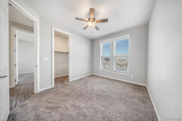 an empty room with windows and ceiling fan