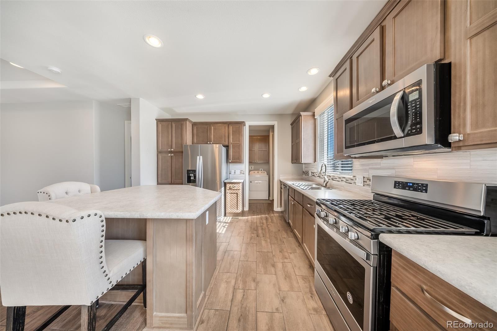 551 Summit Trail Granby, CO 80446 - Photo 6 of 35 a kitchen with stainless steel appliances a stove a sink a microwave a refrigerator white cabinets and wooden floor