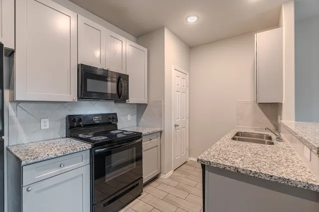 a kitchen with stainless steel appliances granite countertop a stove microwave and sink