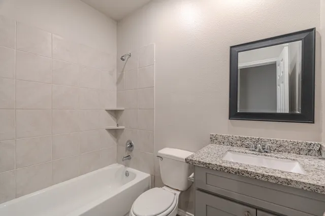 a bathroom with a granite countertop toilet a sink and bathtub