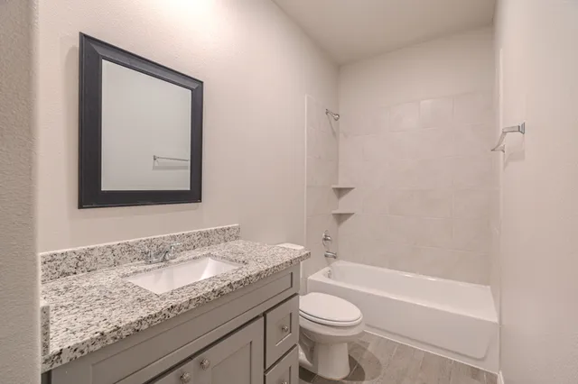 a bathroom with a granite countertop sink mirror vanity and toilet