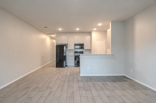 a view of kitchen with granite countertop cabinets and refrigerator