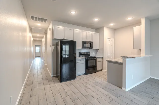 a kitchen with granite countertop a refrigerator and a stove top oven