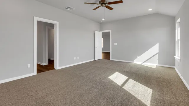 an empty room with a ceiling fan and carpet